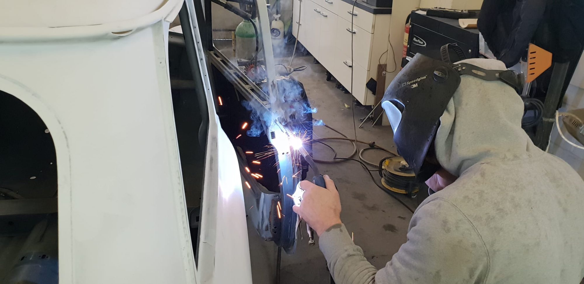 A Bailey Bodyshop technician welding a car door.